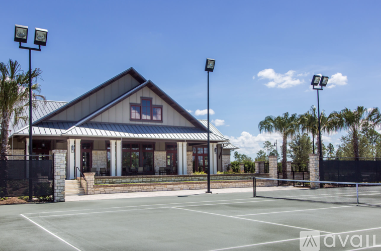 A tennis court is in front of a building with a black fence surrounding it.