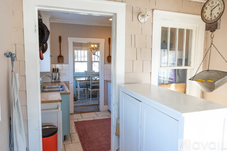 A kitchen with a white cabinet and a red rug on the floor.