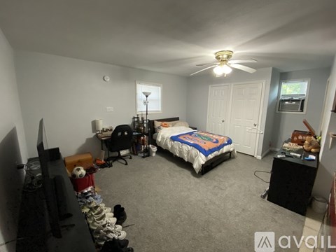 A bedroom with a bed, desk, and a ceiling fan.