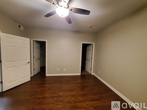 A room with a ceiling fan and wooden floors.