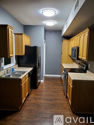 A kitchen with wooden cabinets and a black refrigerator.