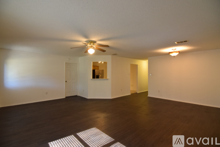 A spacious room with a ceiling fan and wooden flooring.
