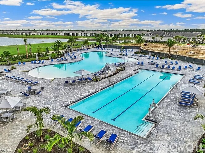 A large outdoor swimming pool surrounded by lounge chairs and umbrellas.