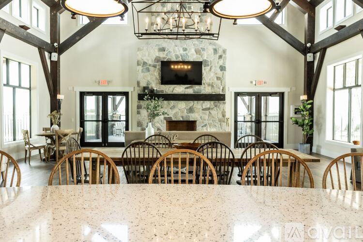 A large dining room with a stone fireplace and wooden chairs.