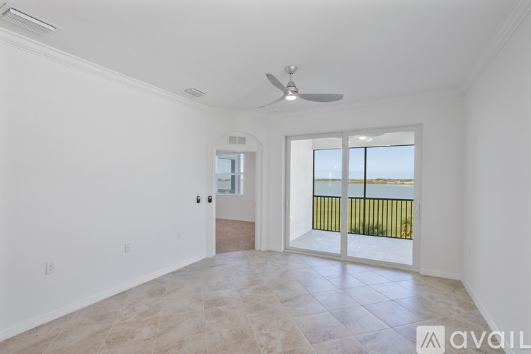 A spacious room with a ceiling fan and sliding glass doors leading to a balcony.