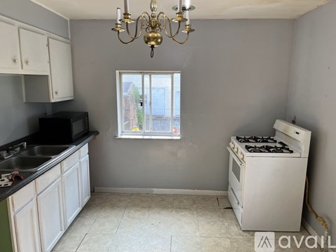 A kitchen with a stove, sink, and cabinets.