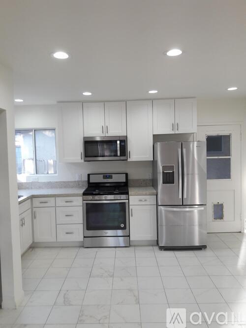 A kitchen with white cabinets and appliances.
