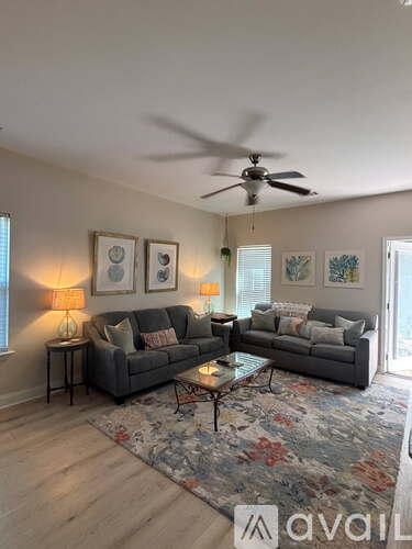 A living room with a grey couch, a coffee table, and a ceiling fan.