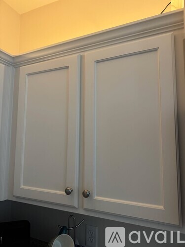 Two white kitchen cabinets with silver knobs.