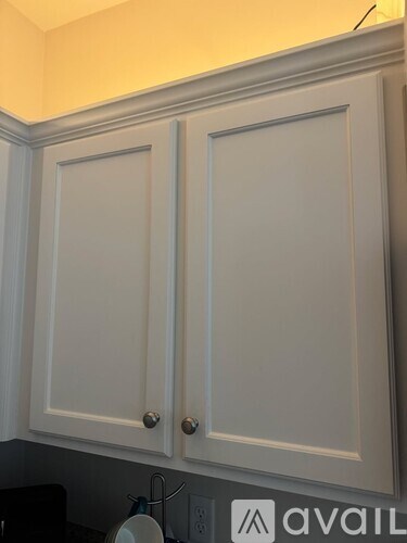 Two white kitchen cabinets with silver knobs.