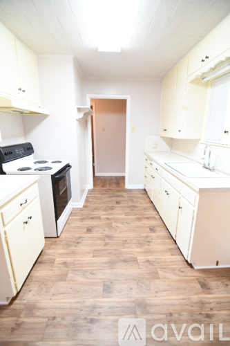 A kitchen with white cabinets and a wooden floor.