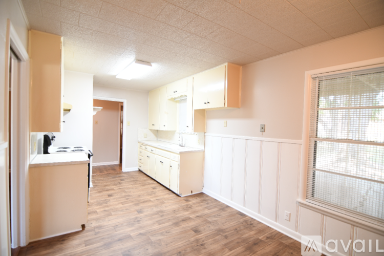 A kitchen with white cabinets and a wooden floor.