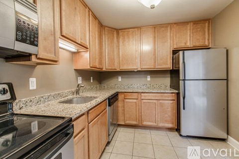 A kitchen with wooden cabinets and a stainless steel refrigerator.