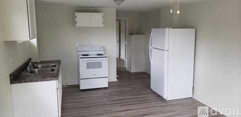A kitchen with a white stove and refrigerator.