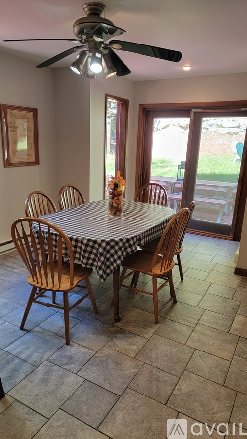 A dining room with a checkered tablecloth and wooden chairs.