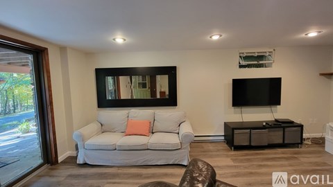 A living room with a white couch and a flat screen TV mounted on the wall.