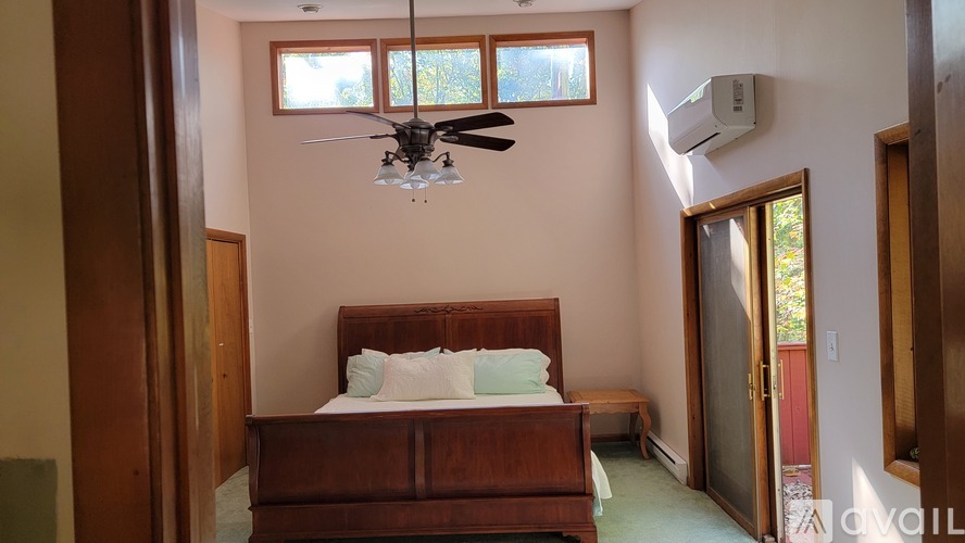 A bedroom with a bed, a ceiling fan, and a window.
