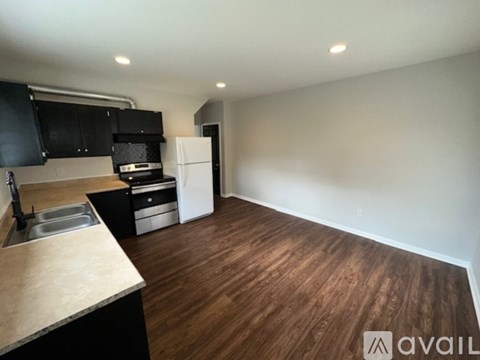 A kitchen with black cabinets and a white fridge.