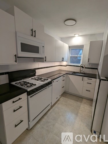 A kitchen with white cabinets and black countertops.