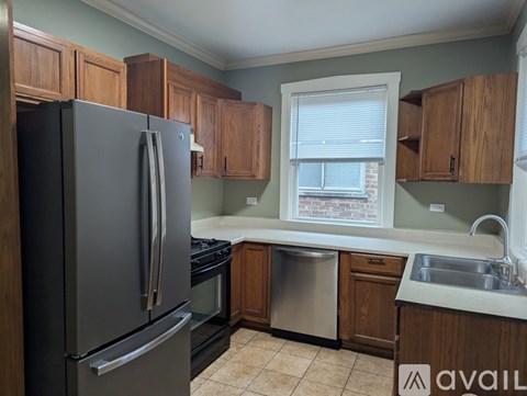 A kitchen with a black refrigerator and wooden cabinets.