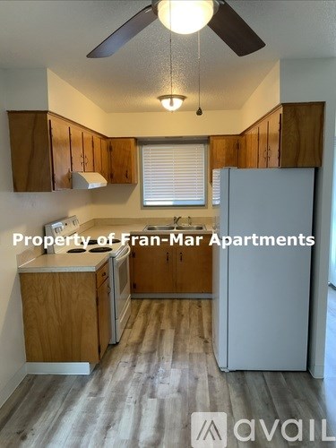 A kitchen with wooden cabinets and a white fridge is available for rent.