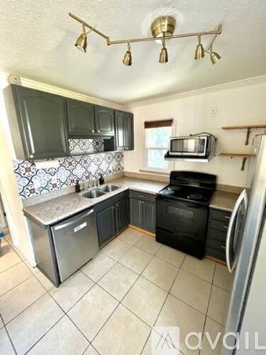 A kitchen with black cabinets and a stainless steel dishwasher.