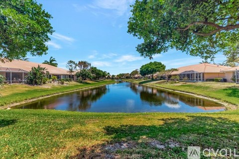 A serene landscape with a pond, houses, and lush greenery.