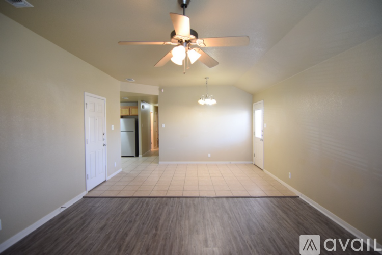 A spacious room with a ceiling fan and a door leading to another room.