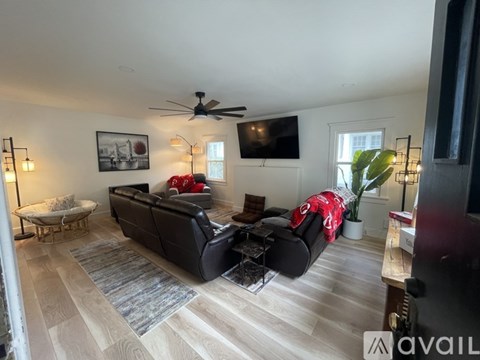 A living room with a black couch and a ceiling fan.