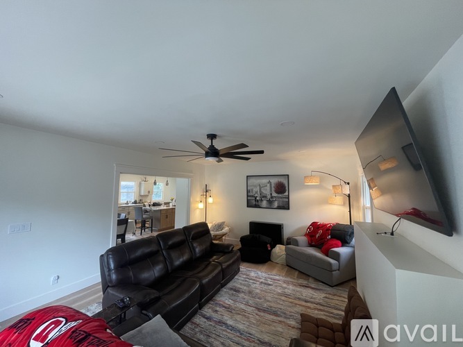 A living room with a black leather couch and a ceiling fan.