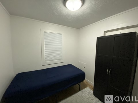 A bedroom with a bed, a wardrobe, and a window with blinds.