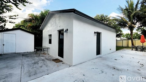 A white house with a black door and a small patio area.