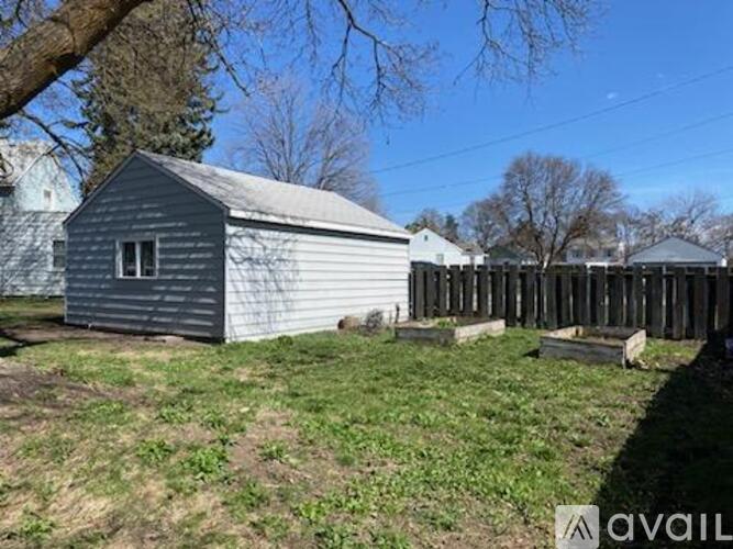 A small grey building sits in a grassy field.