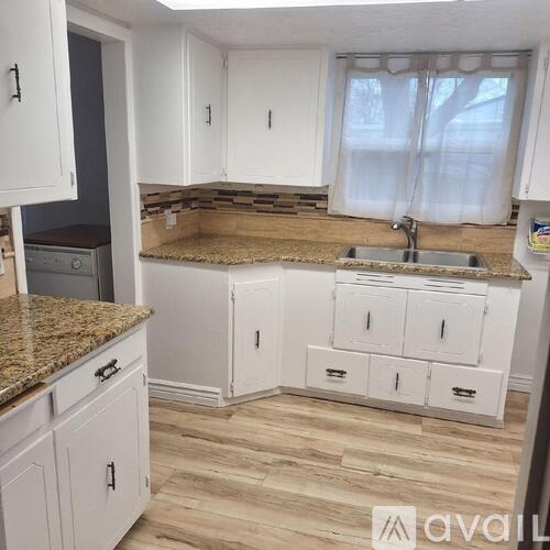 A kitchen with white cabinets and a granite countertop.