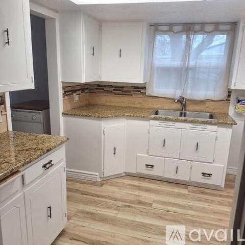 A kitchen with white cabinets and a granite countertop.