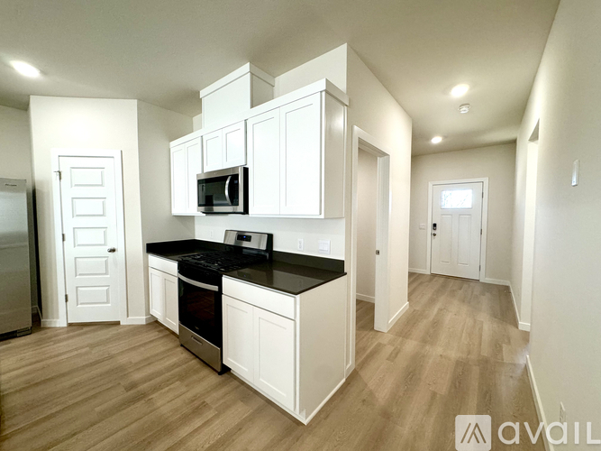 A kitchen with white cabinets and a black countertop.