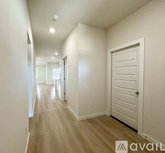 A long hallway with a white door on the right.