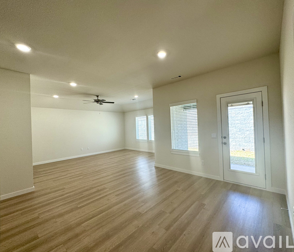A spacious room with wooden flooring and a ceiling fan.