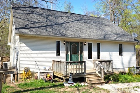 A small white house with a green door and a porch.