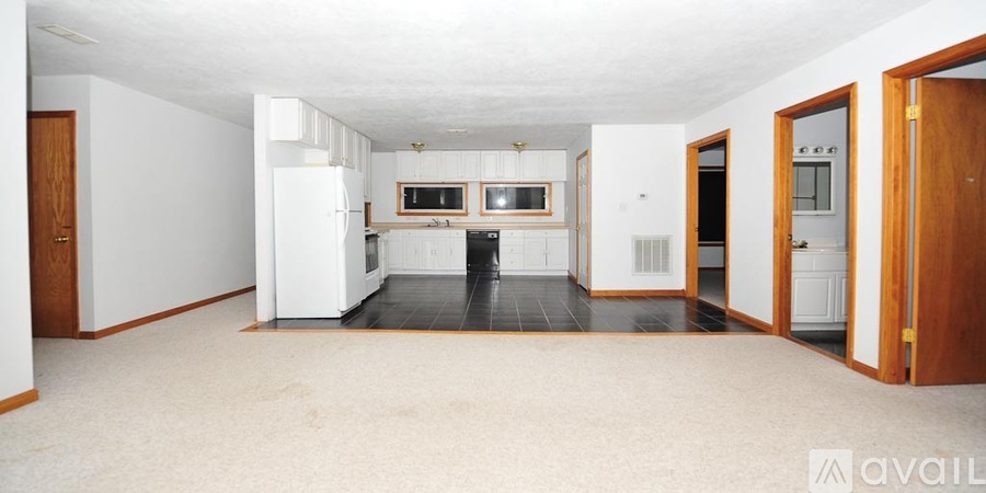 A spacious kitchen with white appliances and a black floor.