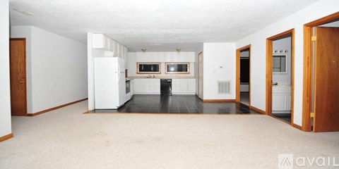 A spacious kitchen with white appliances and a black floor.