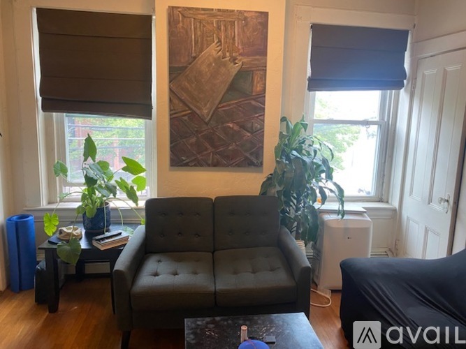 A living room with a grey couch, a coffee table, and a painting on the wall.