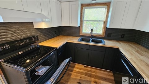 A kitchen with black appliances and wooden floors.