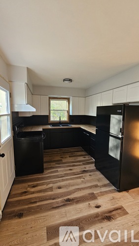 A kitchen with black appliances and wooden floors.