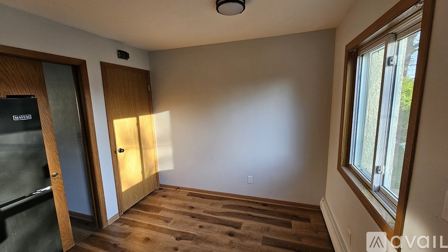 A room with wooden floors and a window on the right side.
