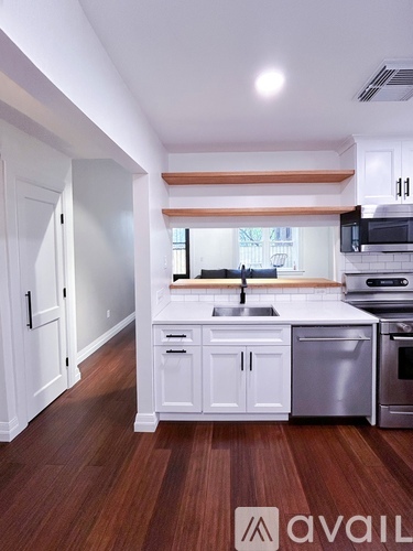 A kitchen with white cabinets and a wooden floor.