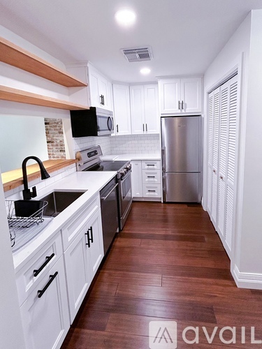 A kitchen with white cabinets and a wooden counter top.