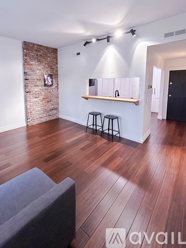A living room with a grey couch and a brick wall.