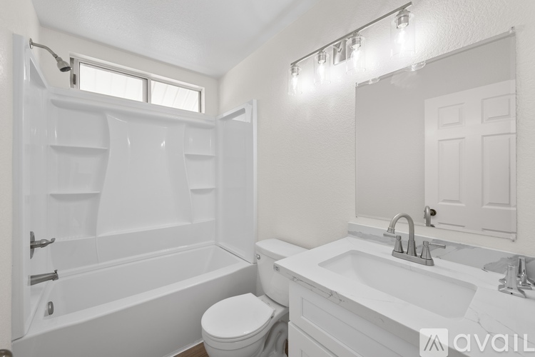 A white bathroom with a toilet, sink, and bathtub.