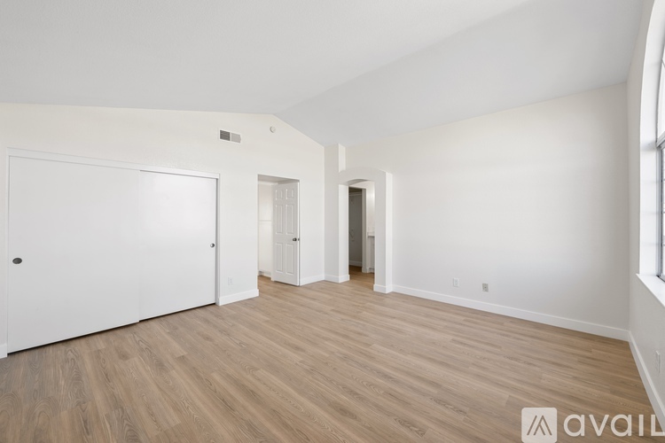 A spacious room with wooden flooring and white walls.